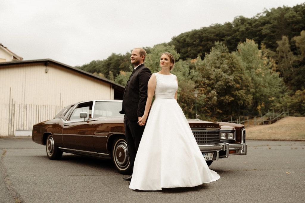 Hochzeitsfotograf in Bad Salzdetfurth macht Brautpaarshooting Hand in Hand mit Oldtimer Wagen